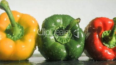 Colorful peppers in super slow motion receiving water