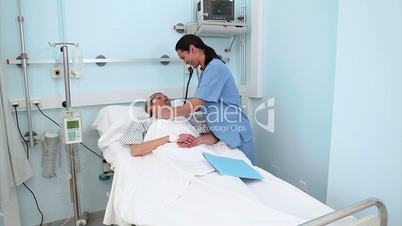 Nurse using a stethoscope on a patient