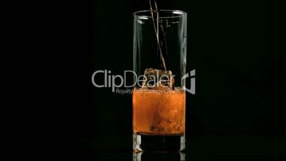 Amber fizzy drink poured in super slow motion