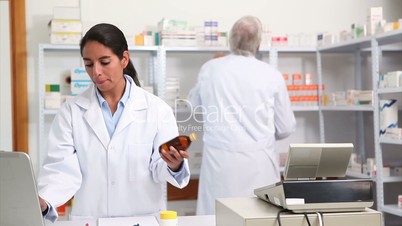 Female pharmacist holding a drug box while smiling