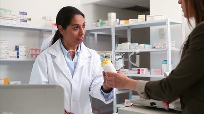 Smiling female pharmacist handing drugs to a customer