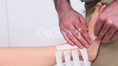 Physiotherapist putting straps on the ankle of a patient