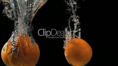 Three oranges diving in super slow motion into water