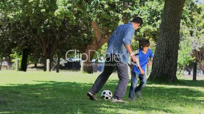 Son and his father playing football in a park