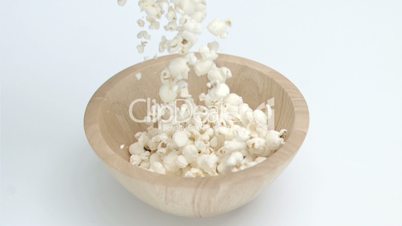 Popcorn in super slow motion falling in a wooden bowl