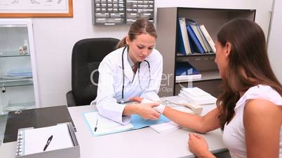 Doctor sitting at her office touching patient wrist