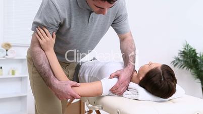 Physiotherapist using his elbow to massage the shoulder of a woman