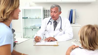 Doctor sitting at his desk writing a prescription