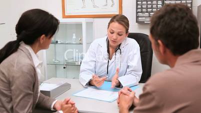 Doctor sitting at her office speaking with patients