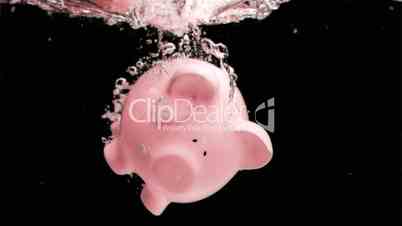 Pink piggy-bank diving in super slow motion into water