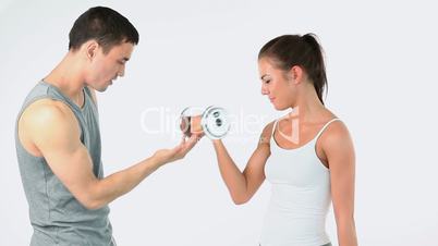 Trainer helping a woman to lift weights