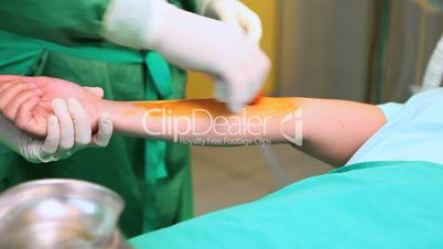 Surgeon disinfecting the forearm of a patient with a compress