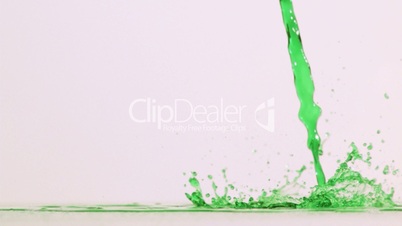 Green liquid poured in super slow motion on a surface