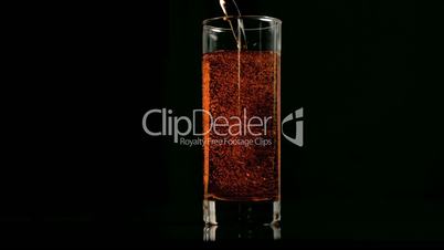 Amber fizzy drink poured in super slow motion in a glass