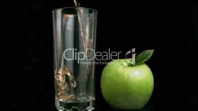 Fresh apple juice flowing in super slow motion in a glass