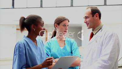 Smiling doctor listening to a nurse holding a clipboard