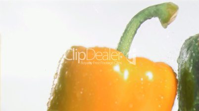 Colorful peppers in super slow motion receiving drops