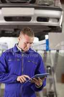 Concentrated mechanic holding a tablet computer
