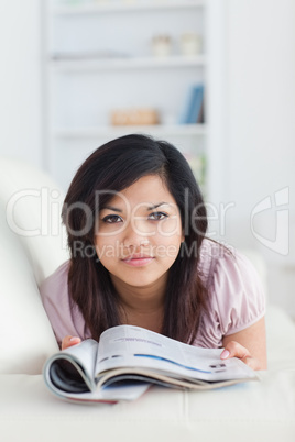 Woman holding a magazine while resting on a couch