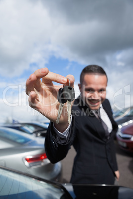 happy dealer holding car keys by his fingertips
