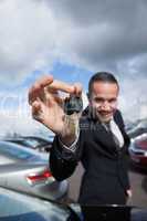 happy dealer holding car keys by his fingertips