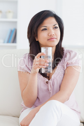 Woman sitting on a couch while crossing her legs and holding a g