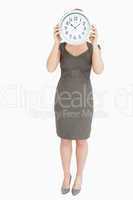 Woman holding a clock hiding her head