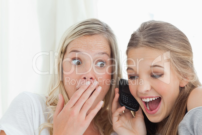 Shocked and happy sisters listening to a phone call