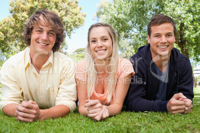Portrait of three smiling students in a park