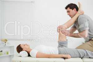 Man massaging a knee while placed it on his shoulder