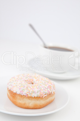 Doughnut with multi coloured icing sugar and a cup of coffee wit