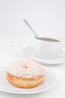 Doughnut with multi coloured icing sugar and a cup of coffee wit