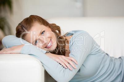 Smiling Woman crossing her arms while lying on a sofa