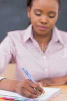 Focus on a black teacher writing on a notebook