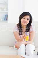 Woman sitting on a sofa while holding a glass of orange juice