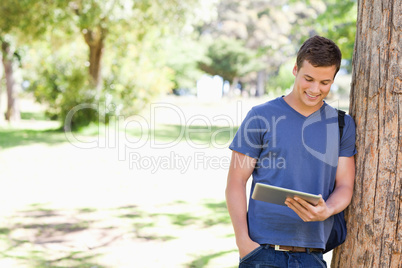 Student leaning against a tree
