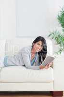 Smiling woman relaxing on a sofa while holding a book