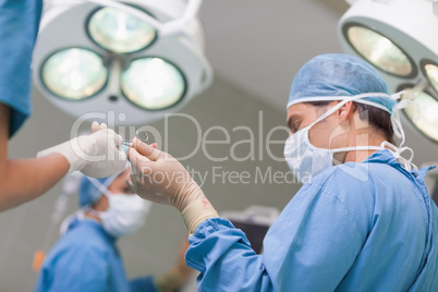 Doctor receiving a surgical scissor from a nurse