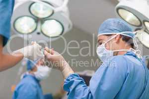 Doctor receiving a surgical scissor from a nurse