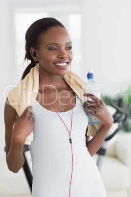 Black woman wearing a towel while holding a bottle