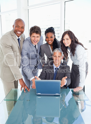 Four business people standing behind their manager proudly showi
