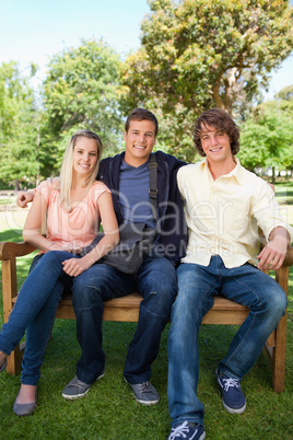 Three smiling students on a bench