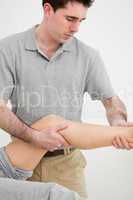 Serious osteopath examining a the leg of his patient