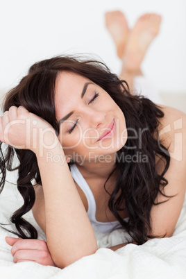 Peaceful woman closing her eyes while lying on her bed