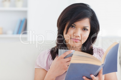 Woman with a book and a mug on her hands