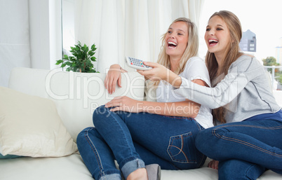 Girls sitting on the couch laughing at the tv