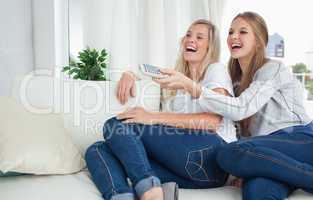 Girls sitting on the couch laughing at the tv