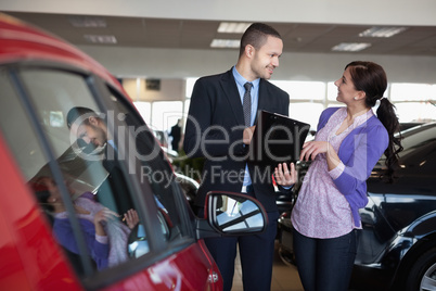 Salesman talking to a smiling woman next to a car