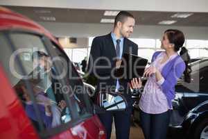 Salesman talking to a smiling woman next to a car