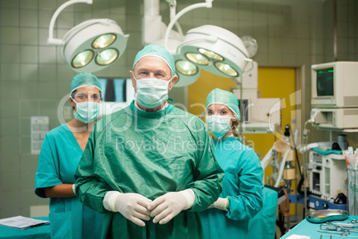 Surgeon joining his hand with two interns behind him